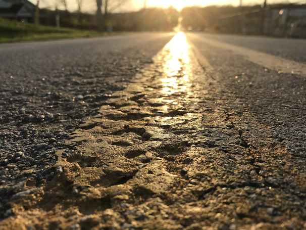 Close-up of fresh asphalt being laid on a city street at sunrise.