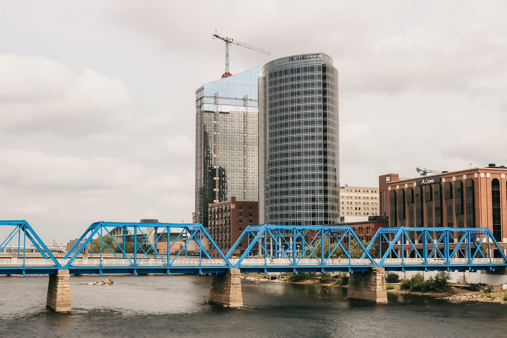 Puente de metal azul sobre el río cerca de los edificios de la ciudad durante el día