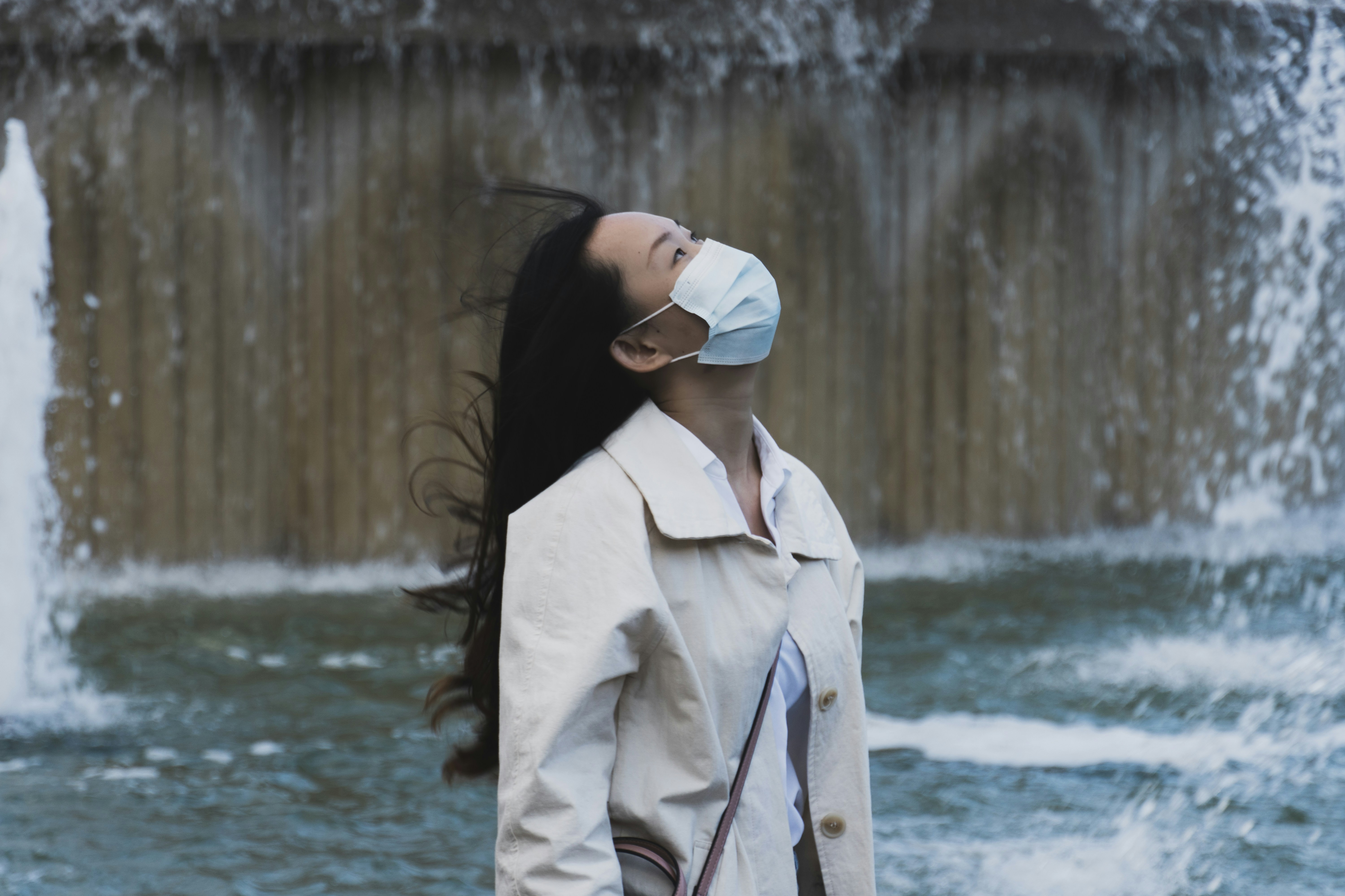 A woman applying a hydrating face mask with cucumber slices on her eyes.