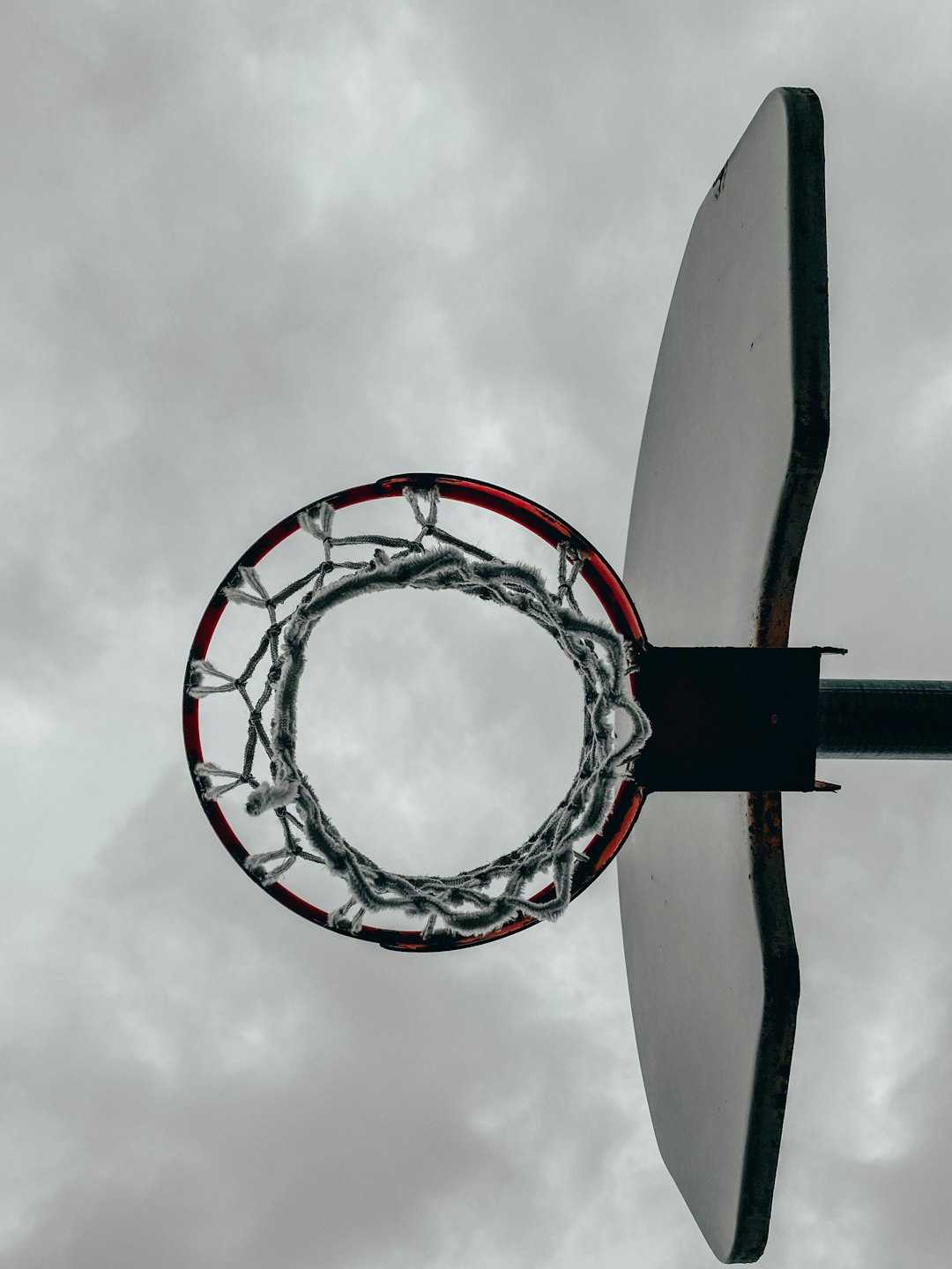 white and red basketball hoop under white clouds during daytime