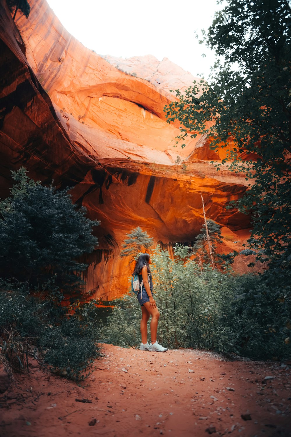 woman in black tank top and blue denim shorts standing on brown rock formation during daytime