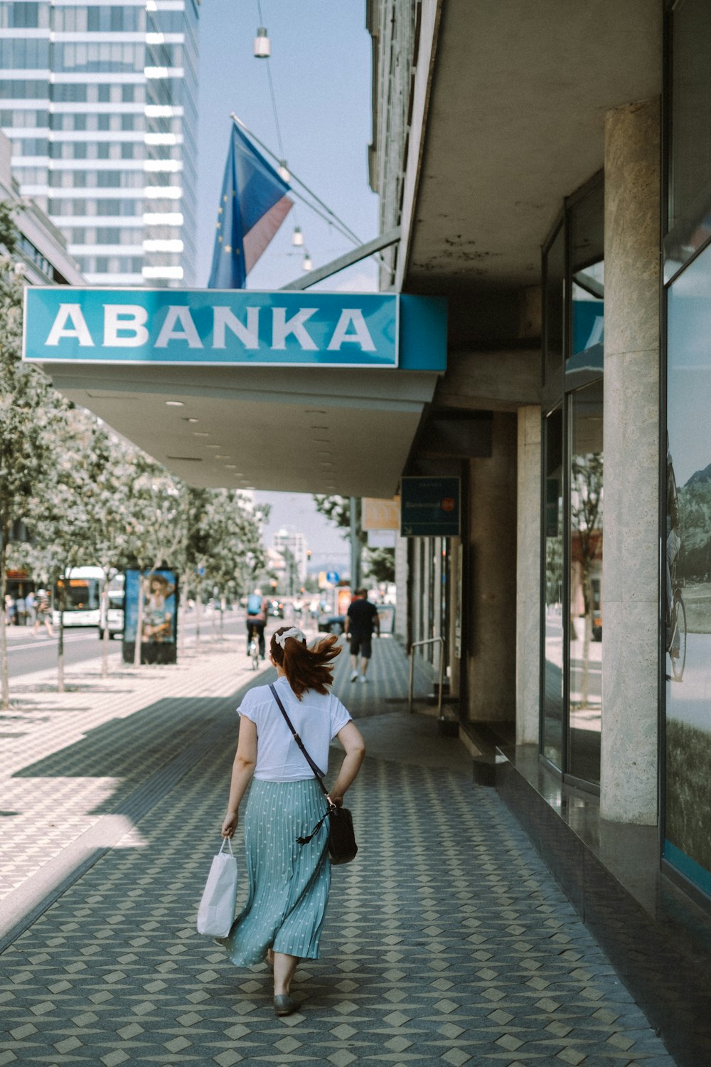 man in white shirt and blue denim jeans walking on sidewalk during daytime