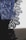 Intricate lace fabric with detailed floral patterns in a deep blue shade is displayed, revealing the fine texture and craftsmanship. The fabric is set against a contrasting light background, emphasizing the delicate design.