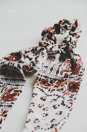 A vibrant scarf with intricate patterns displayed against a minimalist background.