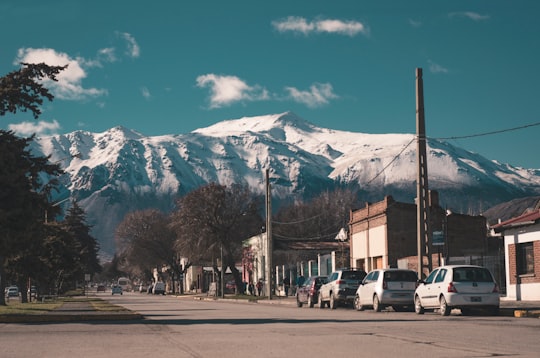cars parked on side of road near trees and snow covered mountain during daytime in Esquel Argentina
