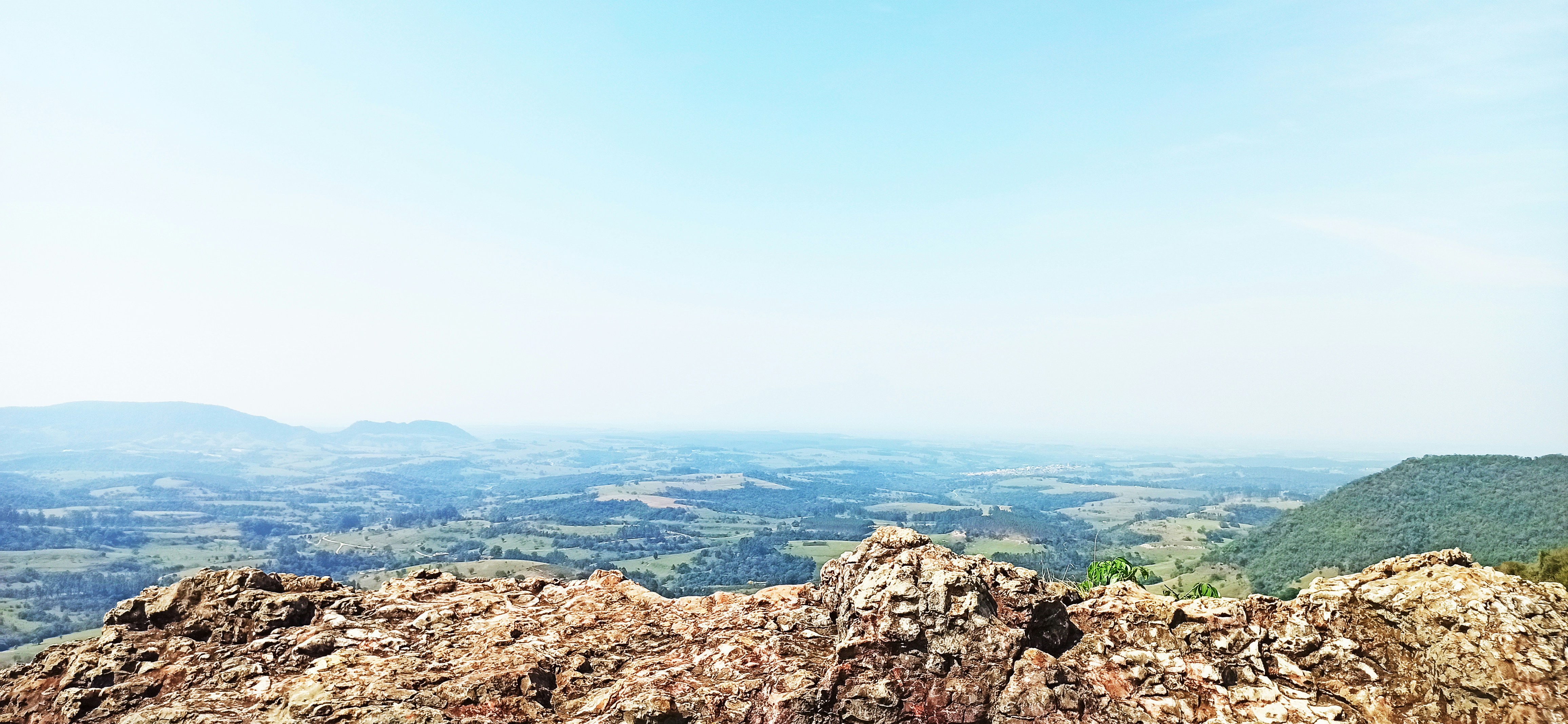 Cumbre de cerro con vista al horizonte, cielo azul intenso, terreno rocoso en primer plano