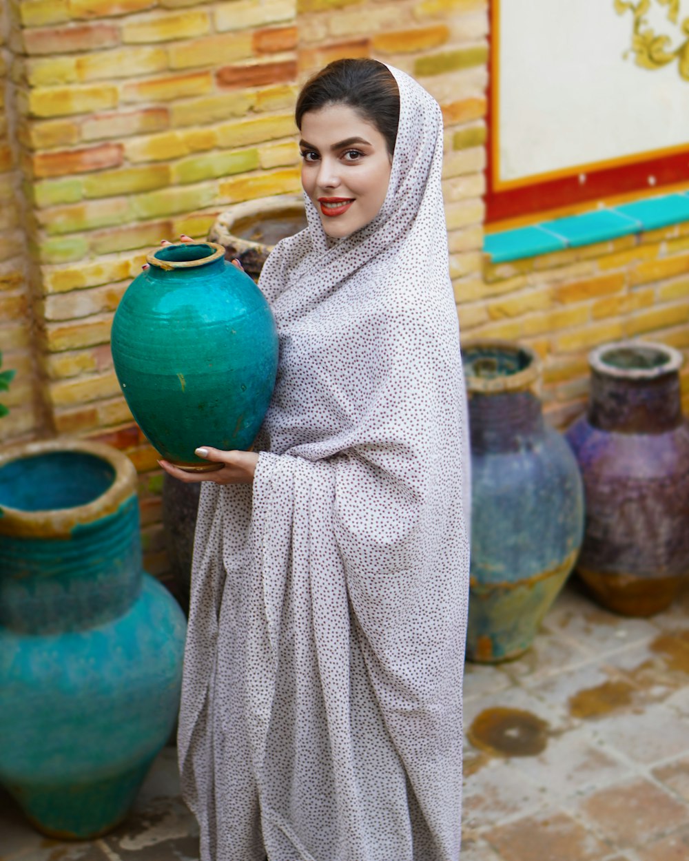 woman in gray hijab standing beside blue propane tank