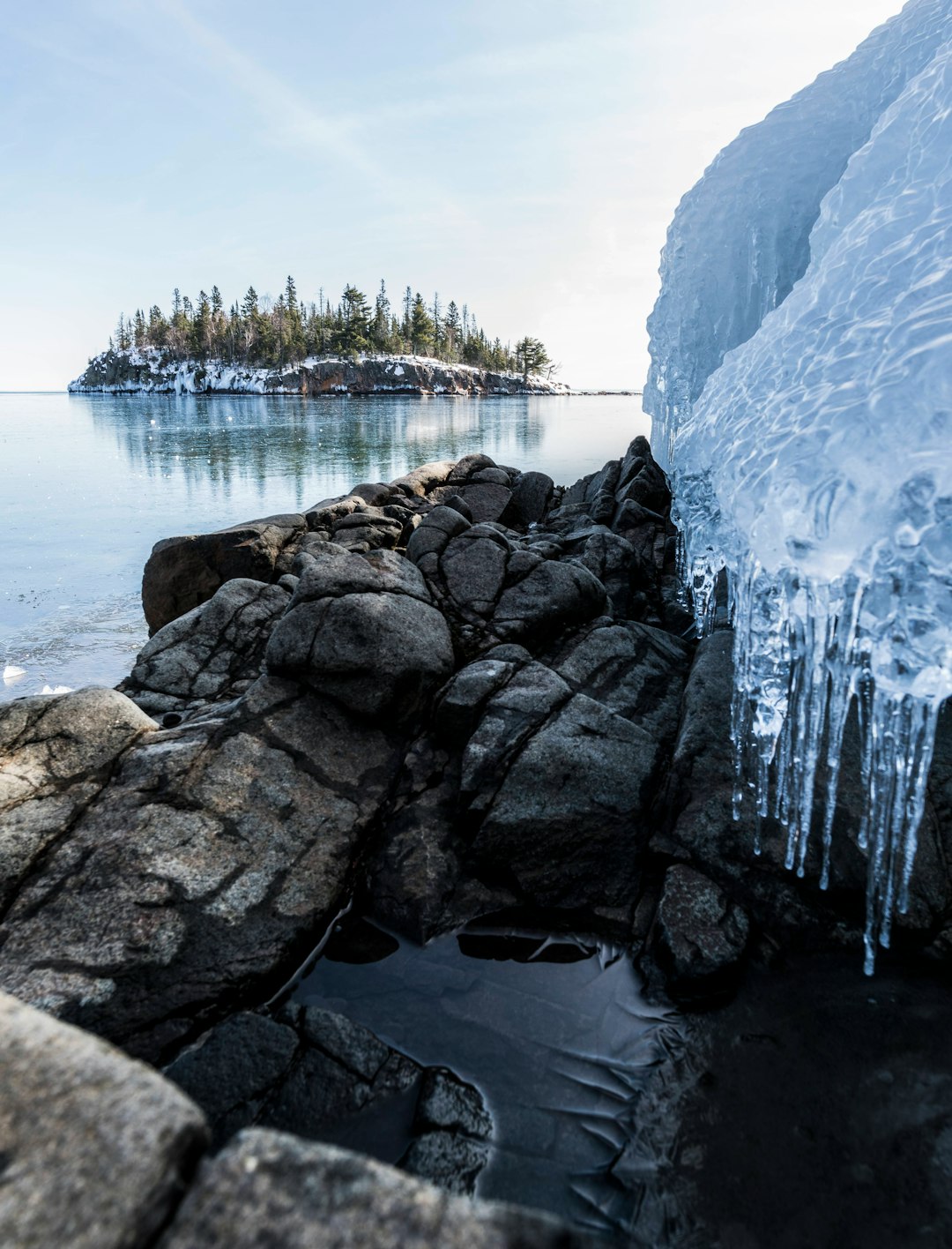 white ice on black rock formation near body of water during daytime