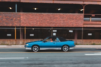A bright blue convertible with the top down, set against a sunny city backdrop.