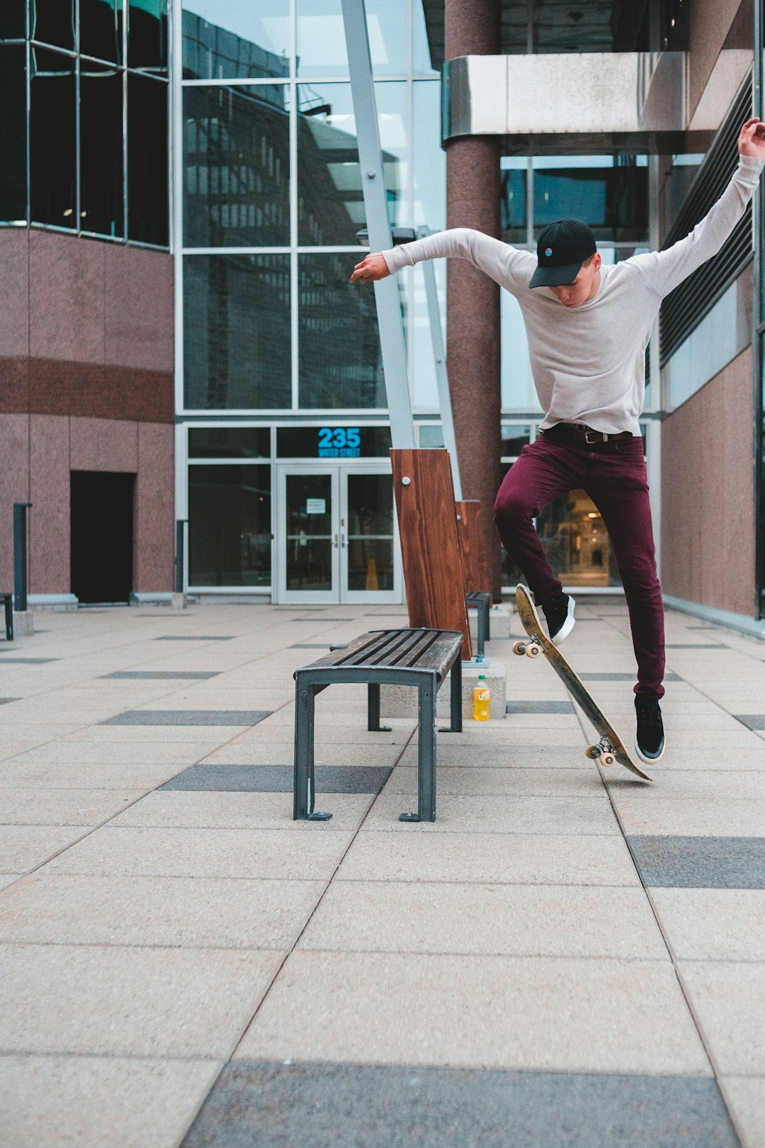 man in gray t-shirt and brown pants jumping on brown wooden bench during daytime