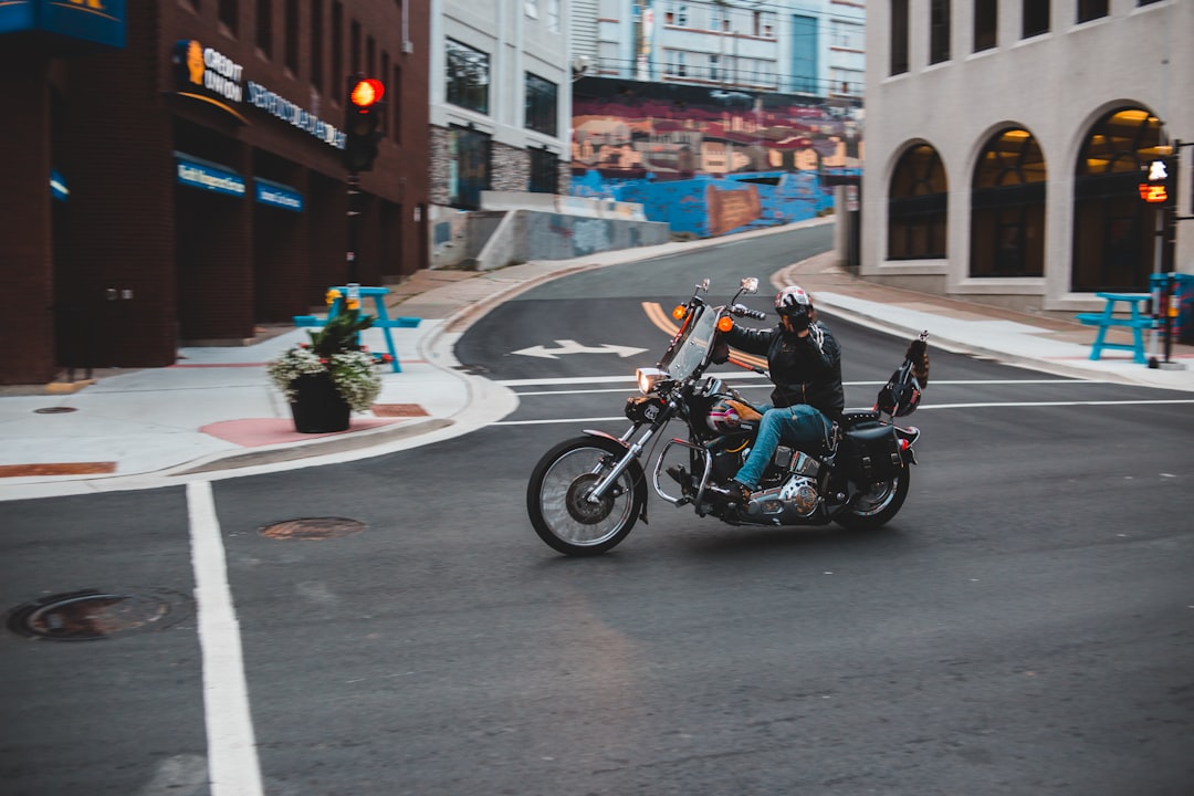 man in black jacket riding on black motorcycle on road during daytime,