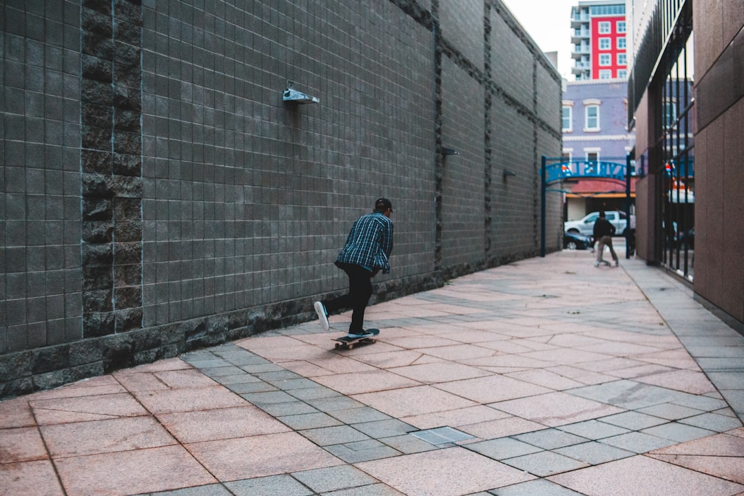 man in blue and black plaid dress shirt walking on sidewalk during daytime