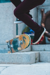 Close-up of a skateboarder’s worn shoes and board mid-trick on a smooth concrete surface.