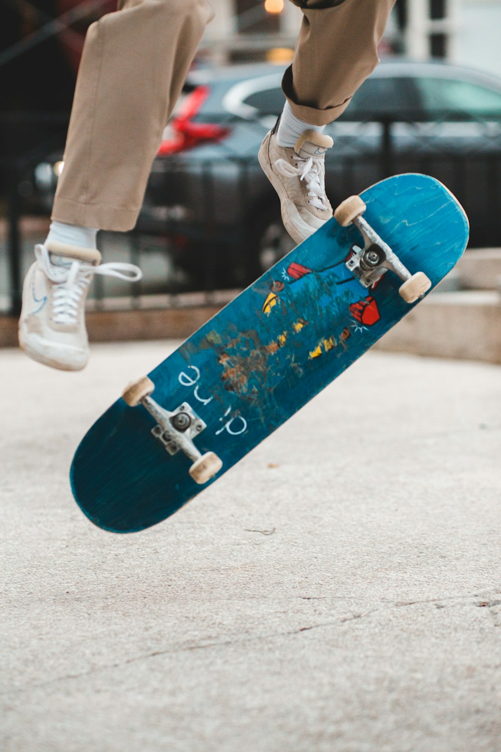 흰색 바지와 흰색 운동화를 신고 파란색 스케이트보드를 타는 사람