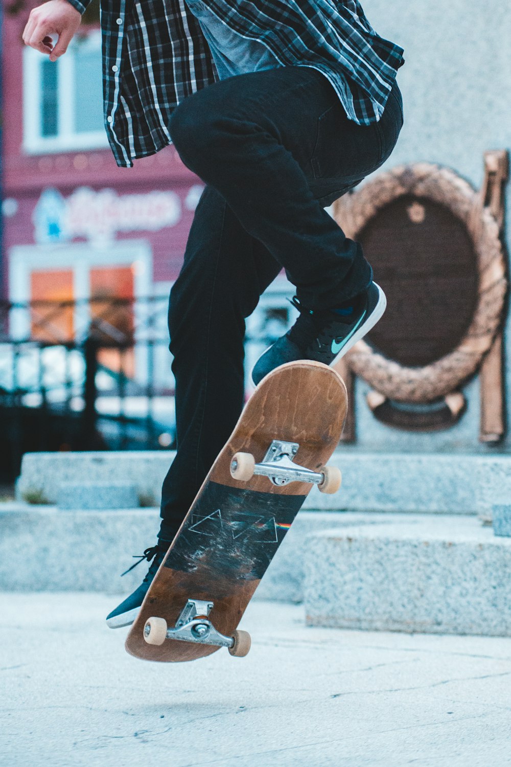 person in black pants and brown and white sneakers standing on brown skateboard during daytime