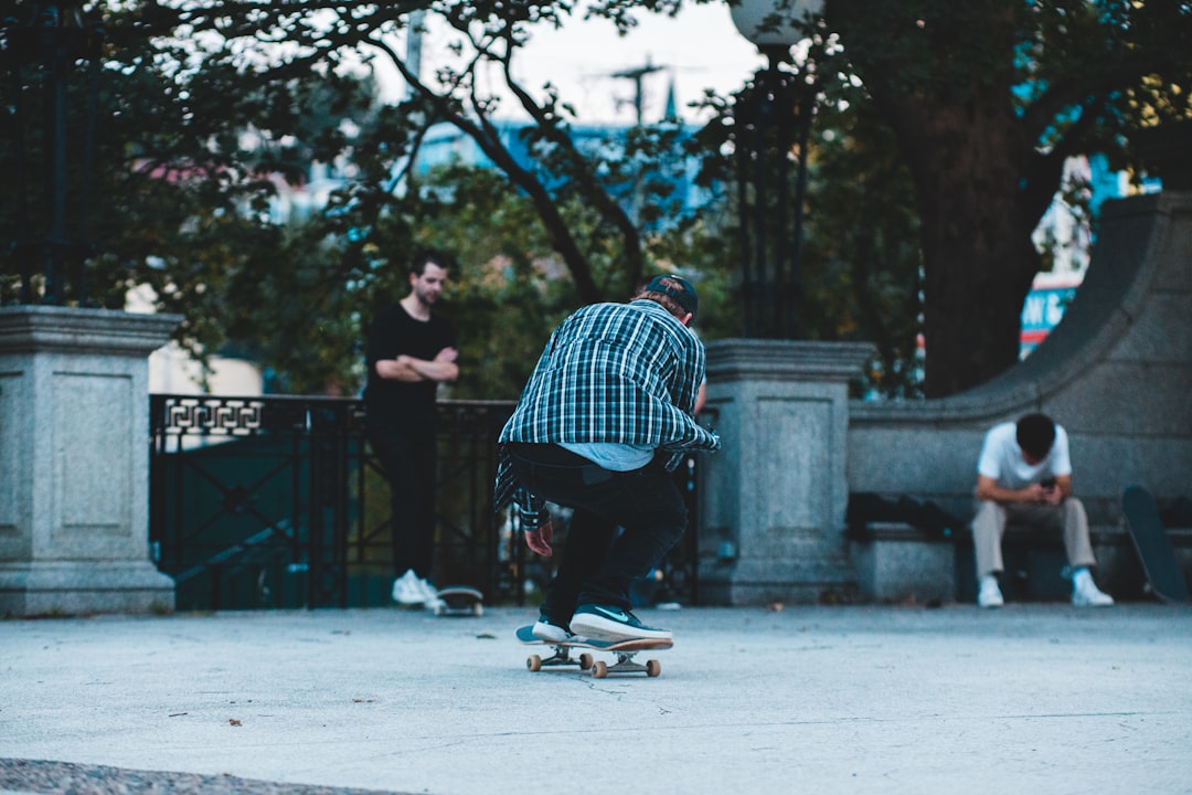 man in blue and white plaid dress shirt and black pants sitting on gray concrete floor