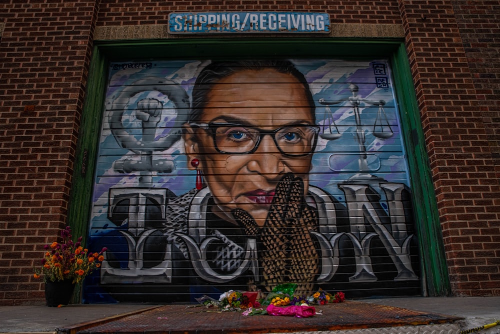 man in black framed eyeglasses standing in front of blue and black wall with graffiti