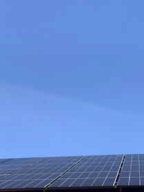 A sleek solar panel angled to catch bright morning sunlight against a clear blue sky.