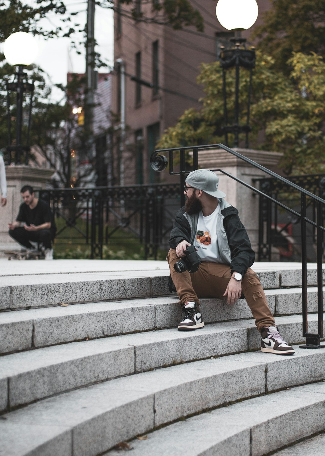 man in white long sleeve shirt and brown pants sitting on gray concrete stairs during daytime