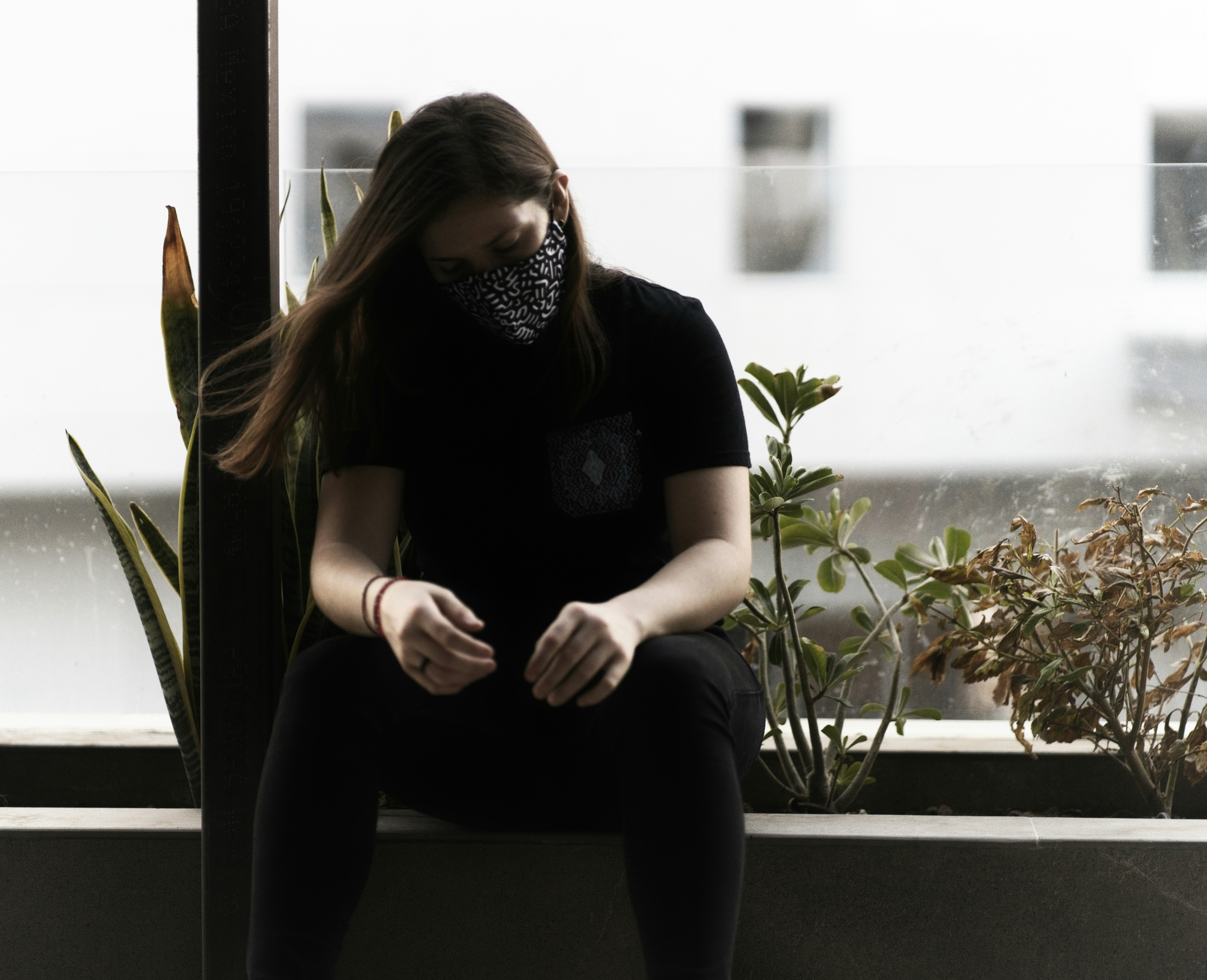 woman in black shirt and black pants sitting on window during daytime