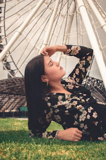woman in black and white floral long sleeve shirt standing on green grass field during daytime