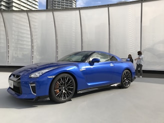 Two locals chatting beside a modern robotaxi parked near the Rhine river.