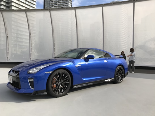 Two locals chatting beside a modern robotaxi parked near the Rhine river.