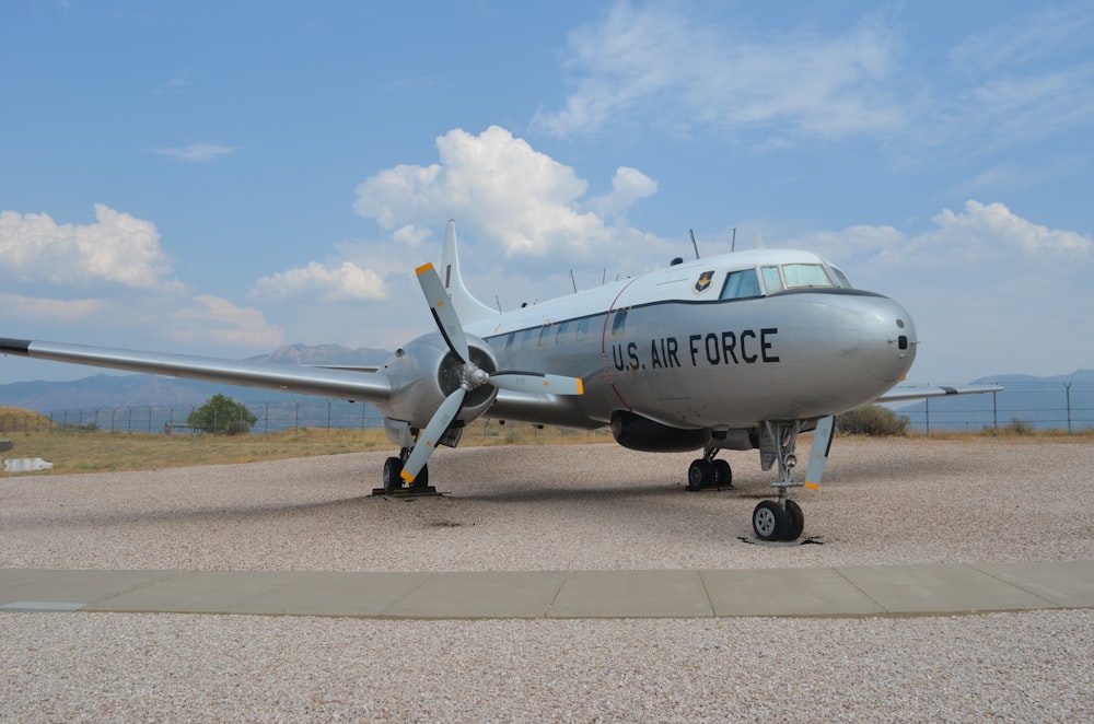 white and blue airplane on gray concrete ground under blue and white cloudy sky during daytime