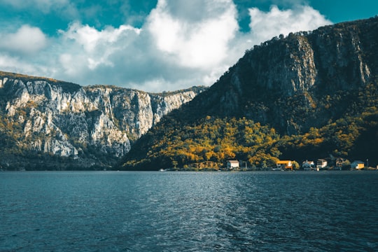 body of water near mountain under cloudy sky during daytime in Dubova Romania