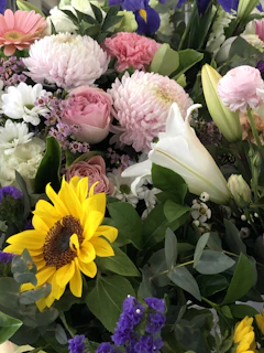 A vibrant birthday flower basket featuring sunflowers, lilies, and roses in warm colors.