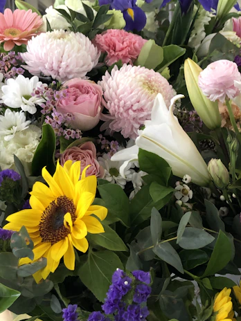 A vibrant birthday flower basket featuring sunflowers, lilies, and roses in warm colors.
