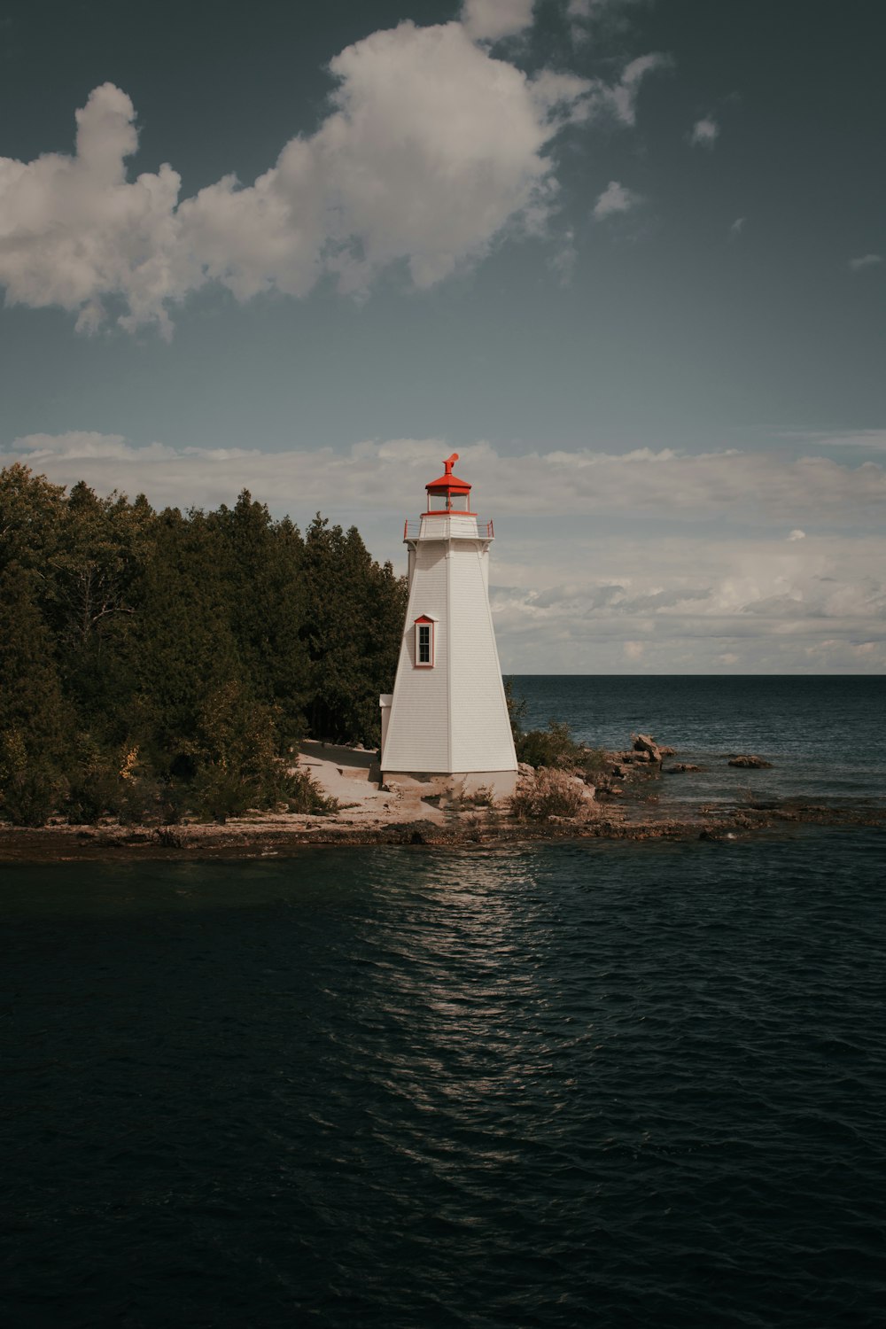 white lighthouse near body of water during daytime