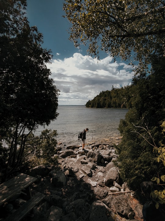 person standing on rocky shore during daytime in Tobermory Canada