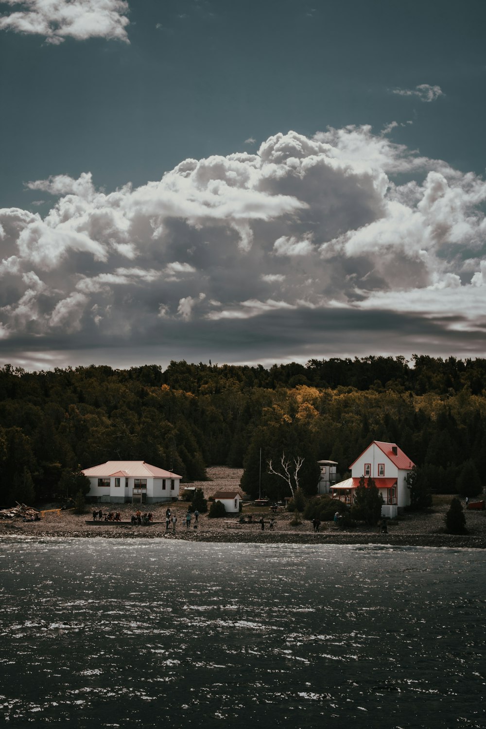  white and brown house near body of water under white clouds and blue sky during daytime