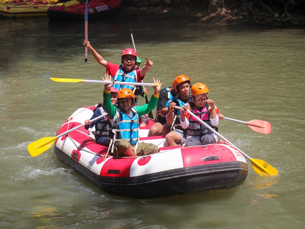 people riding red and white kayak boat on water during daytime