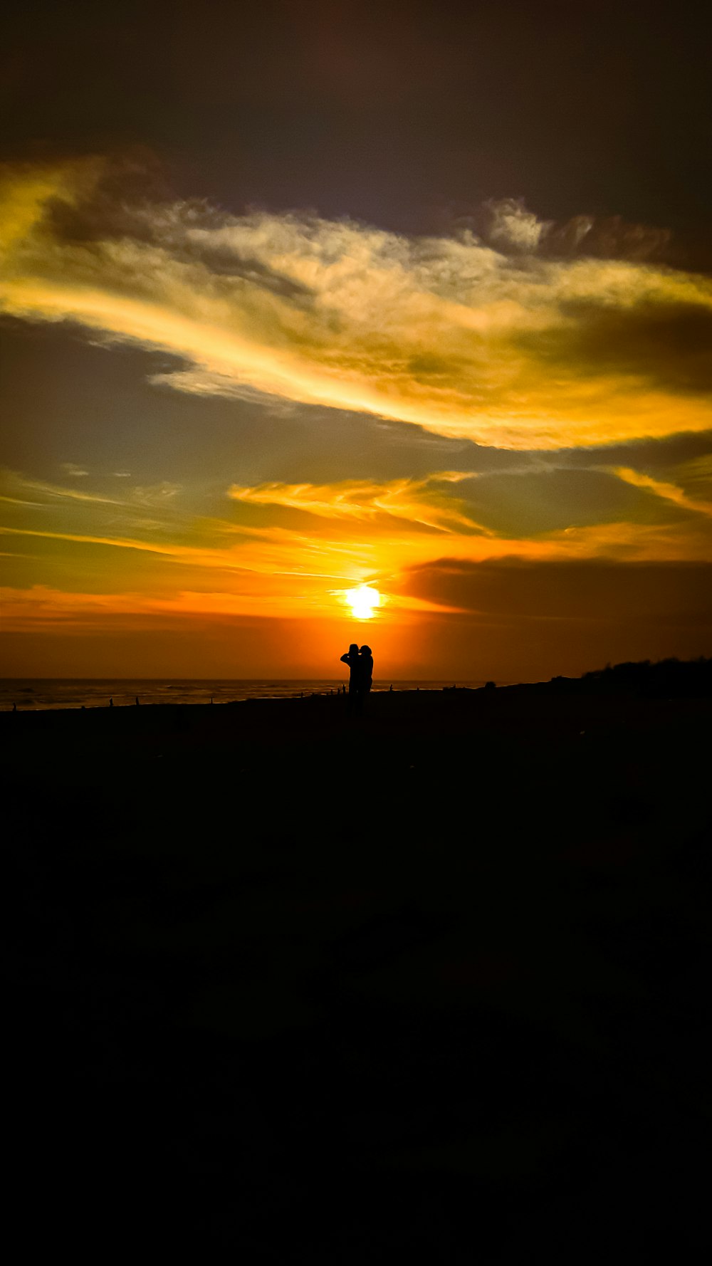 silhouette of person standing on seashore during sunset