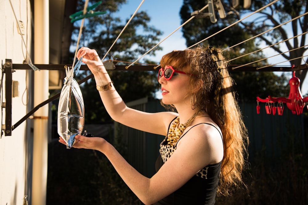 Mujer en camiseta sin mangas negra sosteniendo frasco de vidrio transparente