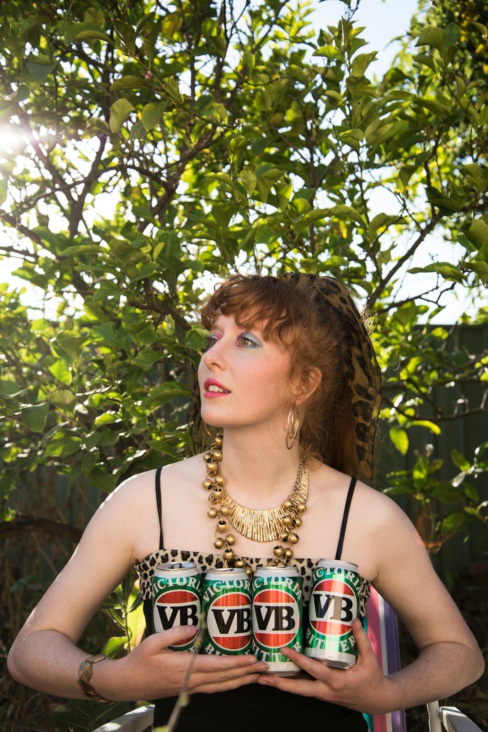 woman in black and white tank top standing under green tree during daytime