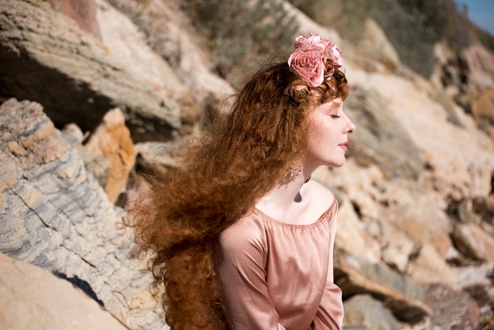 woman in pink shirt standing near brown rock formation during daytime