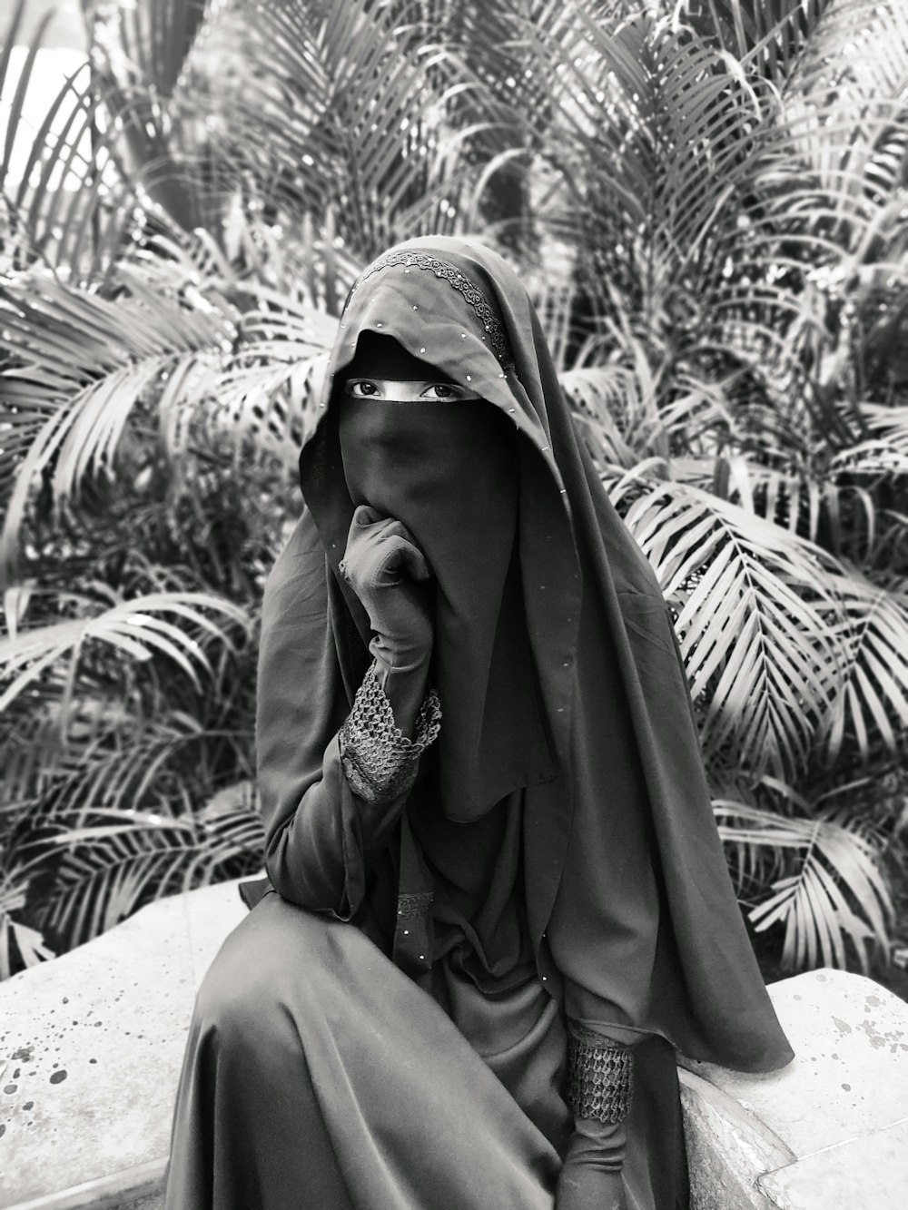 Femme en hijab marron assise sur un textile blanc