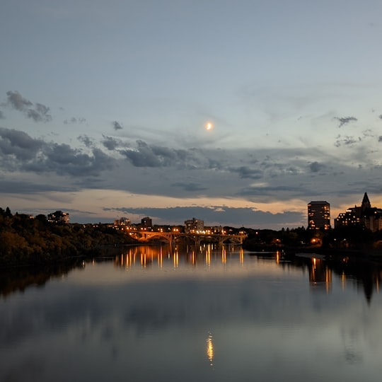 body of water near city buildings during sunset in Saskatoon Canada