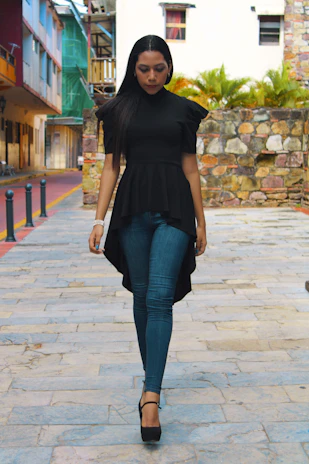 Casual outdoor shot of a woman wearing a vibrant blouse, walking through a city street.