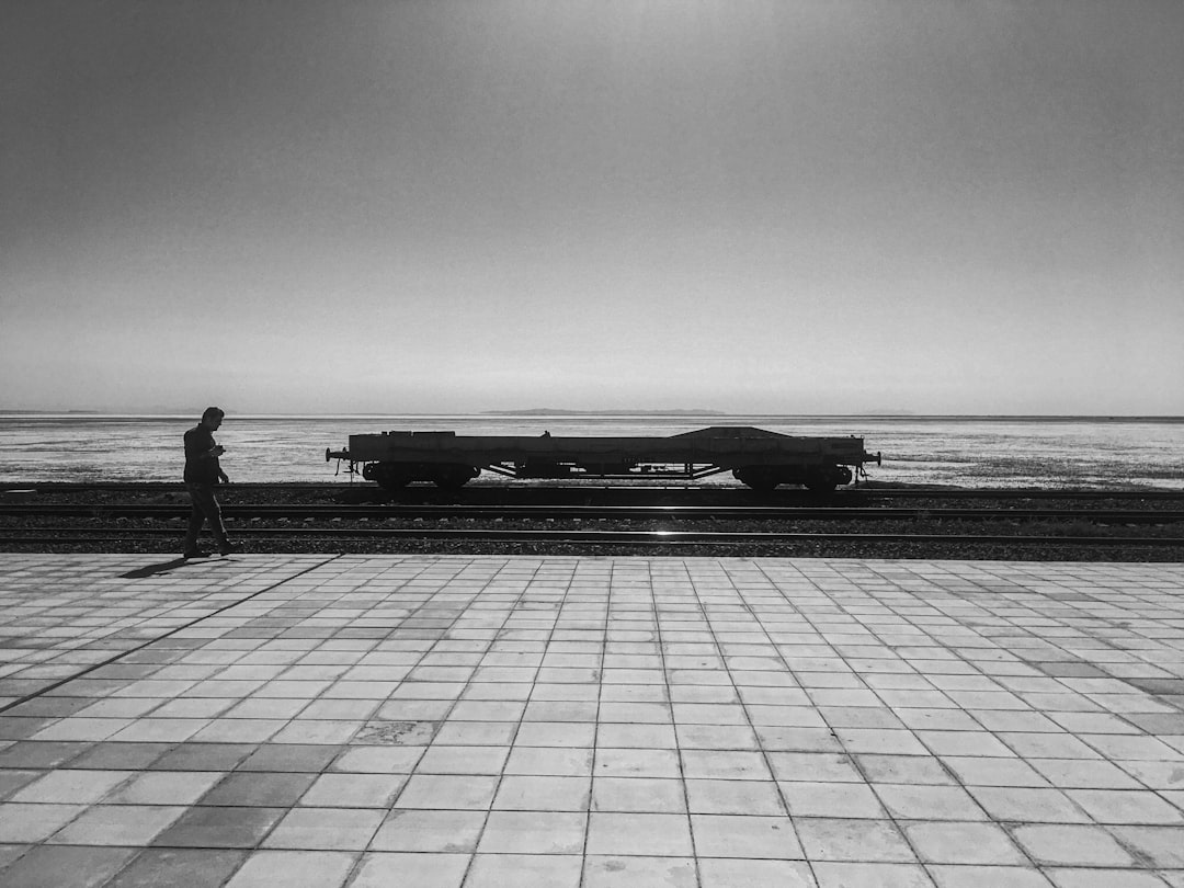 grayscale photo of a man standing on a dock