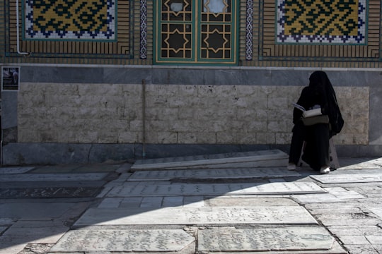 person in black jacket and black pants standing on gray concrete floor in Qom Province Iran