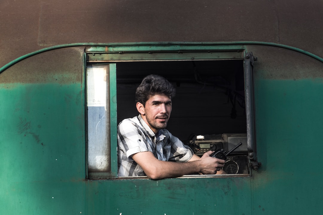 man in white and black plaid button up shirt sitting on green and black bus