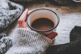 A cozy scene of someone wrapped in a sweater with a powerful statement, holding a cup of coffee.