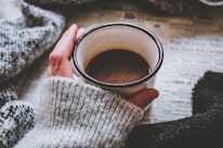 A cozy sweater draped over a chair next to a steaming cup of coffee, creating a warm atmosphere.
