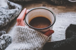 A cozy indoor scene featuring a person lounging in a knit sweater with a warm drink.