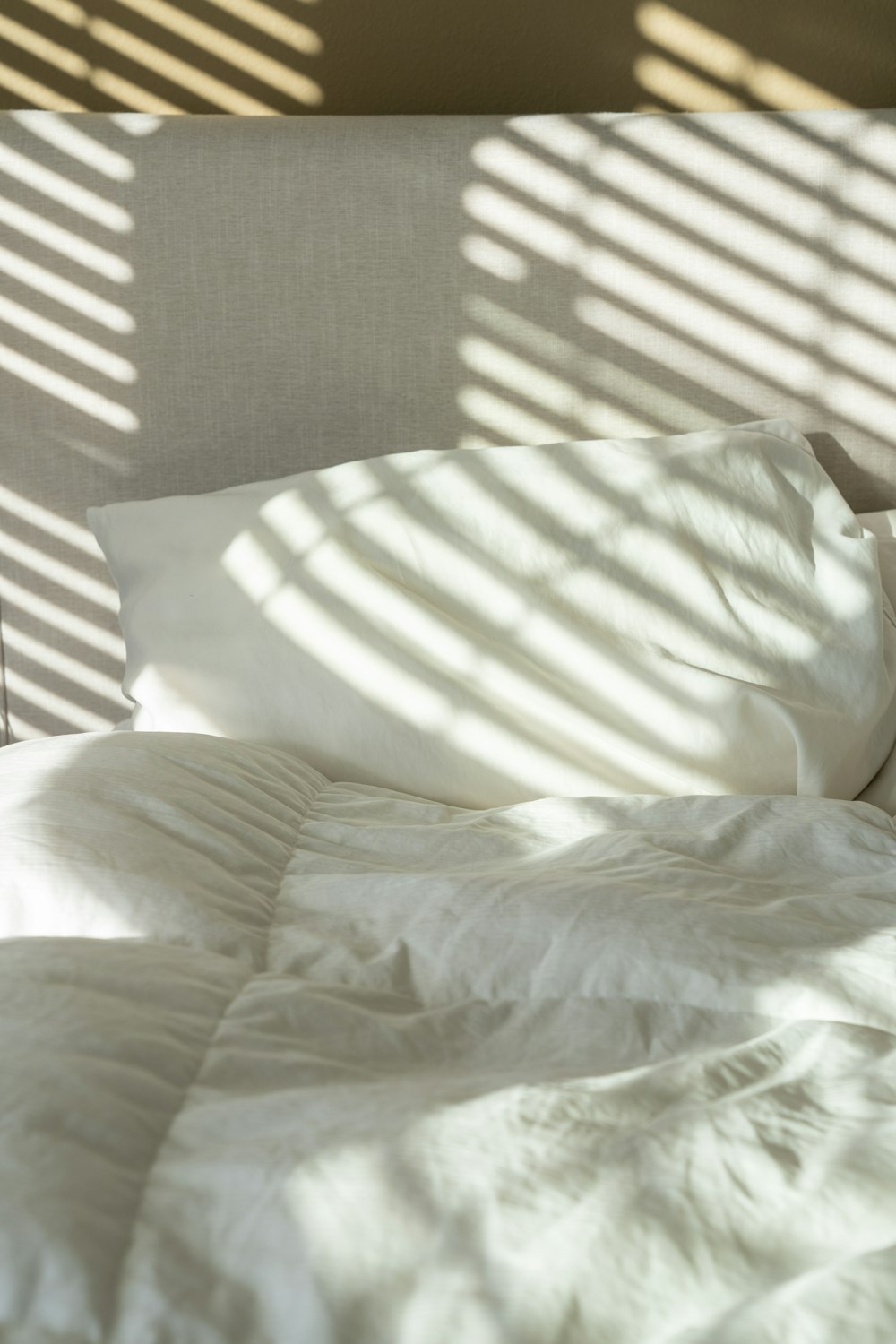 uma cama com lençóis brancos e travesseiros brancos