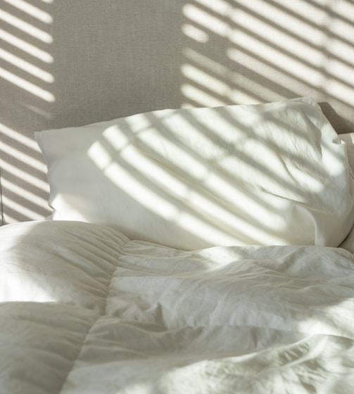 a bed with white sheets and white pillows